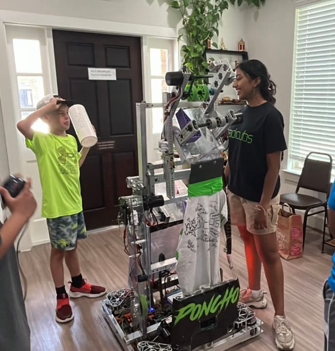 Showing a robot named Poncho to a young visitor at a robotics outreach event