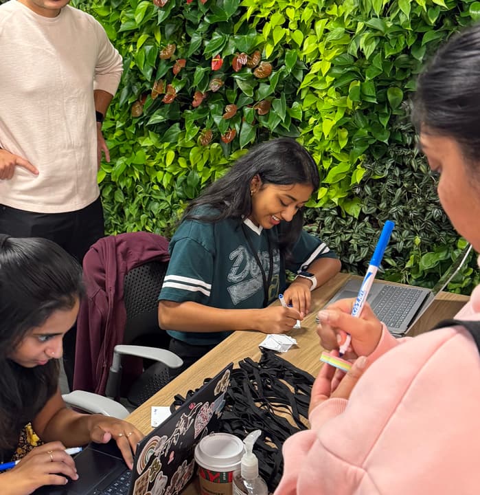 Volunteers at a table writing name tags and checking in guests in front of a living plant wall